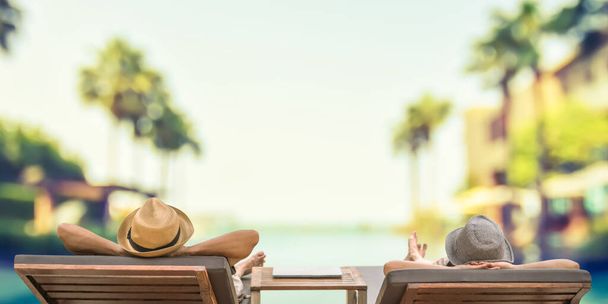 Summer resort hotel stay relaxation with tourist traveller couple take it easy happily resting on beach chair on holiday travel vacation poolside peacefully at tropical beach swimming pool - Fotoğraf, Görsel