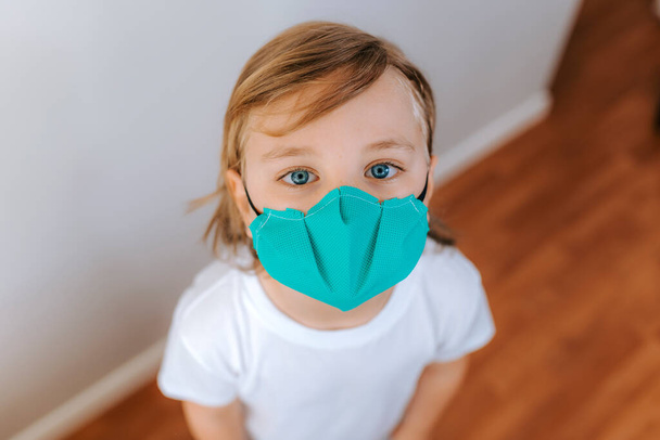 Portrait of little boy with medical face mask looking at camera. child wearing protective mask from virus inside. Concept of health and safety life from coronavirus and pandemic - Photo, Image