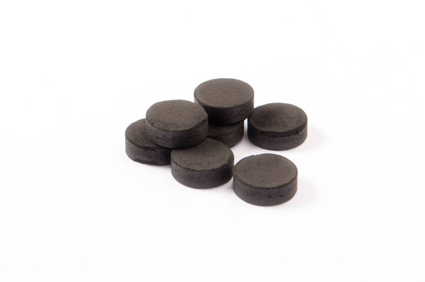 Activated carbon in tablets isolated on white. Medicine and health concept - Photo, Image