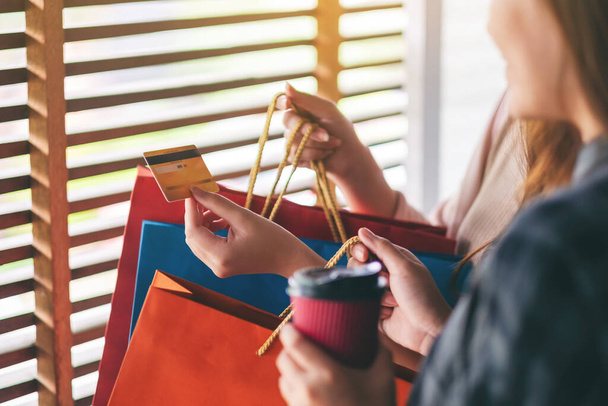 Une femme avec des sacs à provisions tenant et utilisant une carte de crédit pour acheter
 - Photo, image