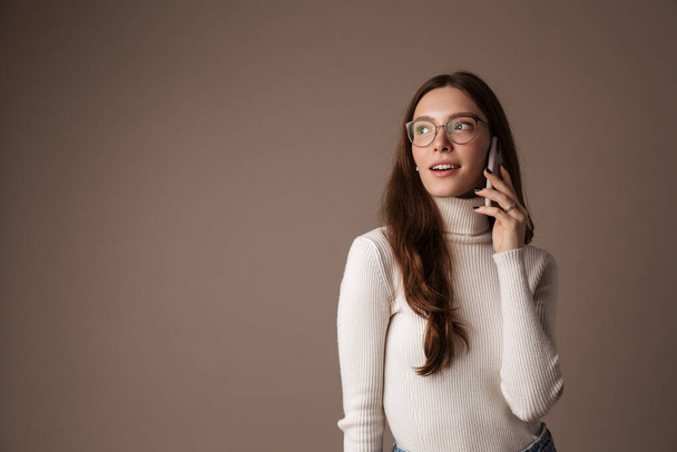 Photo of pleased beautiful woman in eyeglasses talking on cellphone isolated over grey wall - Foto, Imagem