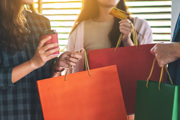 Grupo de personas con bolsas de compras sosteniendo y utilizando una tarjeta de crédito para la compra
 - Foto, imagen