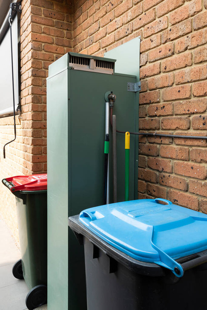 Residential general waste & recycle bins beside hot water service. - Photo, Image