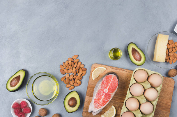Keto-Diät, Low-Carb-Ernährung, gesunde Ernährung. Avocado, Fisch, Öl, Nüsse auf grauem Hintergrund - Foto, Bild