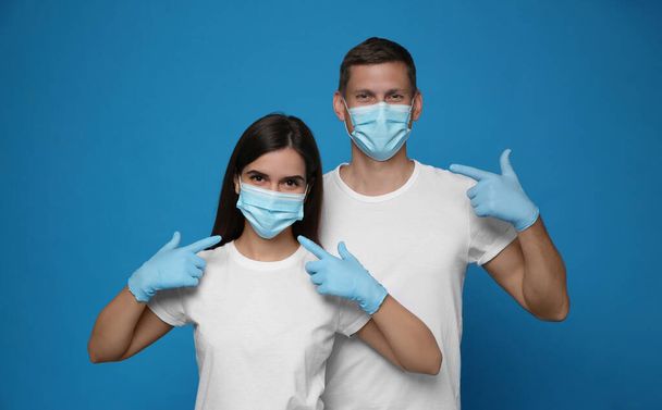 Volunteers in masks and gloves on blue background. Protective measures during coronavirus quarantine - Photo, image