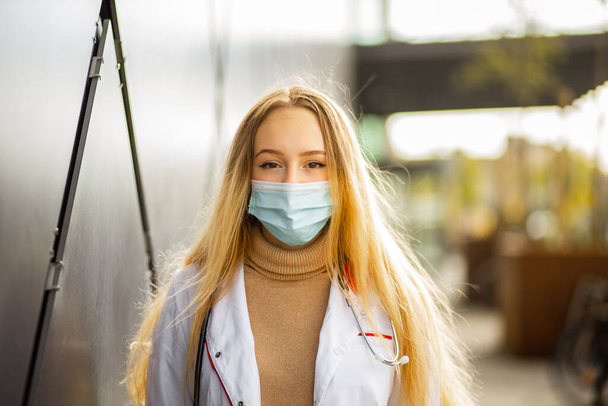 Ritratto di dottoressa o infermiera in maschera chirurgica e camice bianco che la guarda
 - Foto, immagini