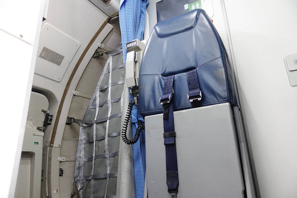 Cabin crew seat in a small aircraft and entrance to the back of the plane - Photo, Image