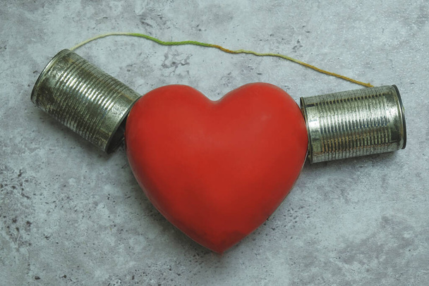 Coeur rouge écoutant étain peut téléphone sur fond gris
 - Photo, image