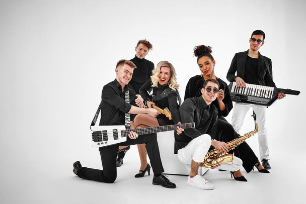 photo of multi ethnic music band in studio.Musicians and woman soloist posing over white background - 写真・画像