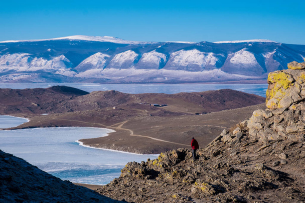 Aventurero explorando la montaña durante el invierno con la vista del lago congelado y la montaña de nieve
 - Foto, imagen