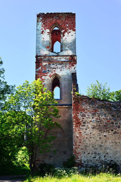 Ancient tower and a brick and stone wall ruins of a gothic Lutheran Church - Foto, imagen
