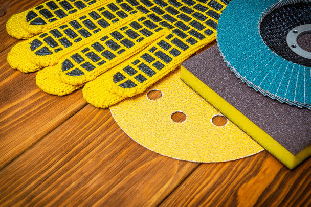 Набір абразивних інструментів і жовтих робочих рукавичок на старовинних дерев'яних дошках майстер використовується для шліфування предметів
 - Фото, зображення