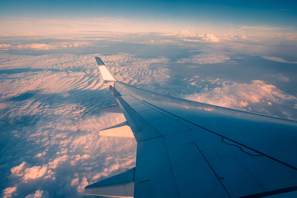 Silhouetvleugel van een vliegtuig bij zonsopgang zicht door het raam. - Foto, afbeelding