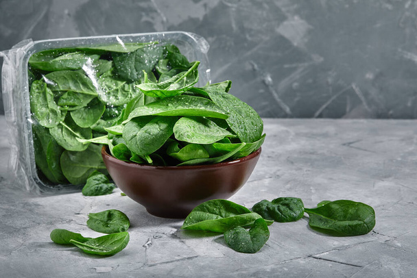 Fresh spinach in an old bowl on a gray background. Selective focus, horizontal. environmental packaging. Delivery of products, copies of space, photos for the catalog of stores. - Photo, Image
