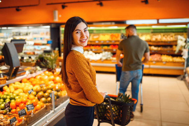 Pareja con carro en supermercado juntos. Hombre y mujer comprando frutas y verduras en el mercado, comprando clientes
 - Foto, imagen