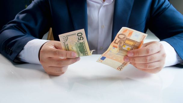 Zakenman die kiest tussen dollars en eurobankbiljetten - Foto, afbeelding