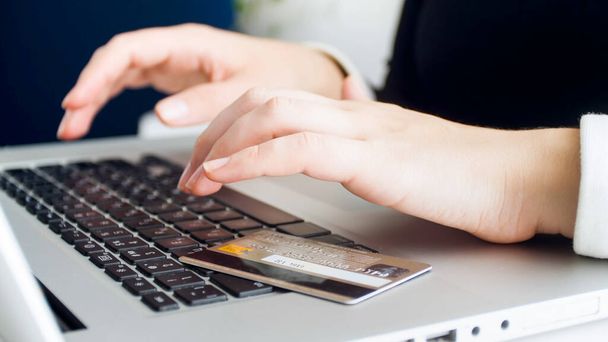 若い女性がインターネットを閲覧しながら、ラップトップのキーボードに横たわっているプラスチッククレジットカード - 写真・画像