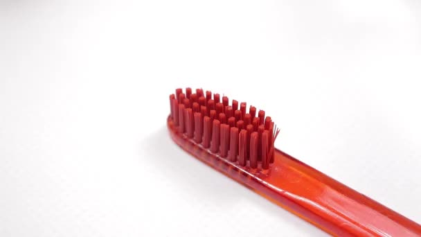 Απλώστε φυσική οδοντόκρεμα σε μια κόκκινη οδοντόβουρτσα. - Πλάνα, βίντεο