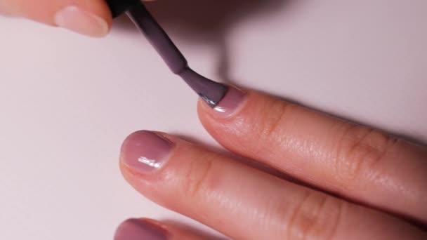 Anwendung von farbigem violetten Gel-Lack auf den Nagel. Maniküre zu Hause. - Filmmaterial, Video