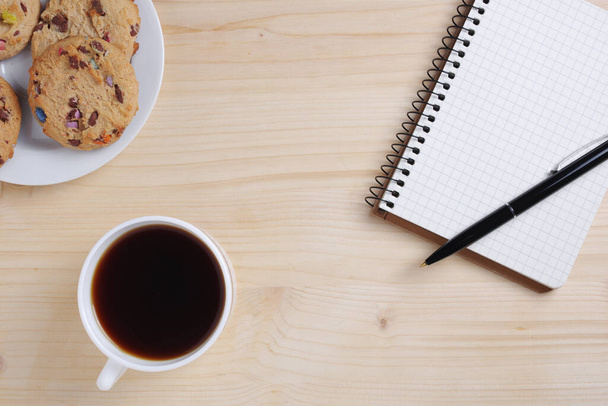 Cup of coffee, cookies and notebook with pen on wooden background, top view - Fotografie, Obrázek