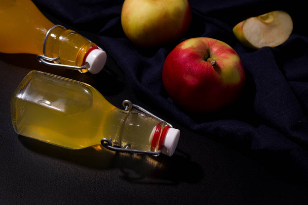 Gefermenteerde appeldrank in flessen op een zwarte achtergrond - Foto, afbeelding
