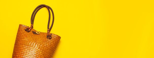 Beach wicker straw or rattan women's eco bag on yellow background. Flat lay top view copy space. Concept of travel. Summer bright background. Beach accessories, women s summer bag, hand bag, fashion. - Фото, изображение