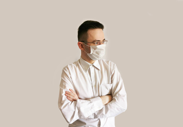 Ein Mann mit medizinischer Maske und Brille blickt in die Ferne. Arzt in Uniform - Foto, Bild