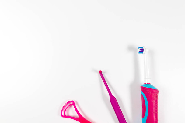 Υπέρηχος ροζ οδοντόβουρτσα και προϊόντα οδοντιατρικής υγιεινής σε λευκό φόντο. Οδοντιατρικά προϊόντα για οδοντόβουρτσα, υγιεινή περιποίηση δοντιών και στοματική υγιεινή - Φωτογραφία, εικόνα