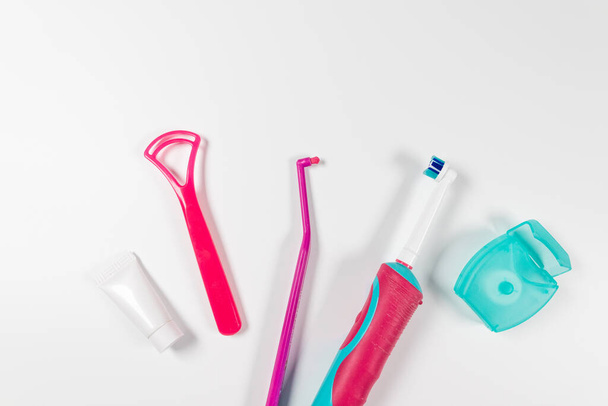Cepillo de dientes rosa ultrasónico y productos de higiene dental sobre un fondo gris. Productos dentales para cepillarse los dientes, cuidar los dientes sanos e higiene bucal
 - Foto, imagen