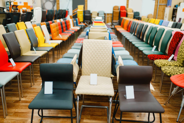 Különböző székek sorai a bútorbolt bemutatótermében, senki. Ülésminták a boltban, áruk a modern belső tér számára - Fotó, kép