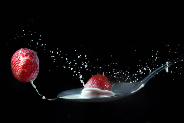 Strawberry bounces on a spoon of milk - Photo, Image