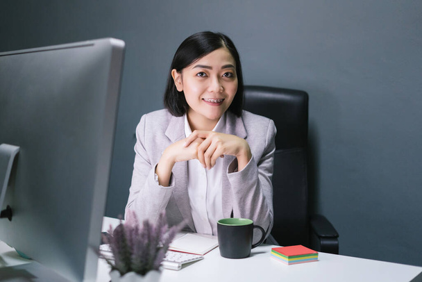 Portraiture of happy asian business woman seating at her office desk with smile face. - Photo, Image
