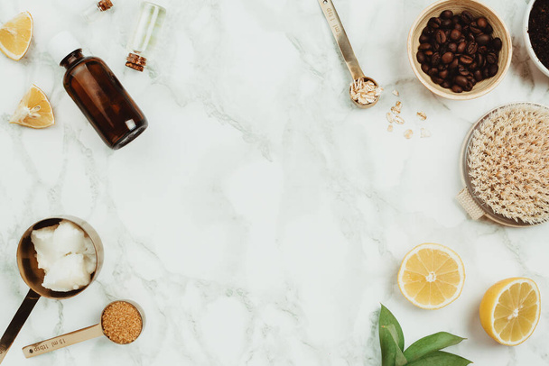 Ingredients for homemade skin scrub on marble: ground coffee, coconut and essential oil, oats, brown sugar, lemons and body brush. Handmade cosmetics concept  - Photo, Image