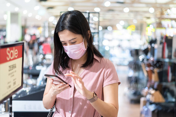 Una donna asiatica che fa shopping nel centro commerciale dopo aver aperto il blocco con maschera rosa e distanza sociale
. - Foto, immagini