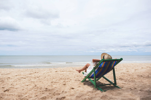 Plaj sandalyesine uzanmış, rahatlamış hisseden bir kadın. - Fotoğraf, Görsel