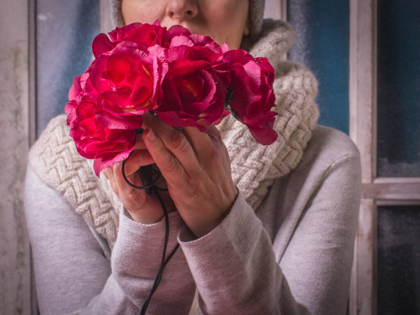 Frau hält weinrote Blumen in der Hand, im Vordergrund Nahaufnahme, Winter mit Liebeskonzept. - Foto, Bild