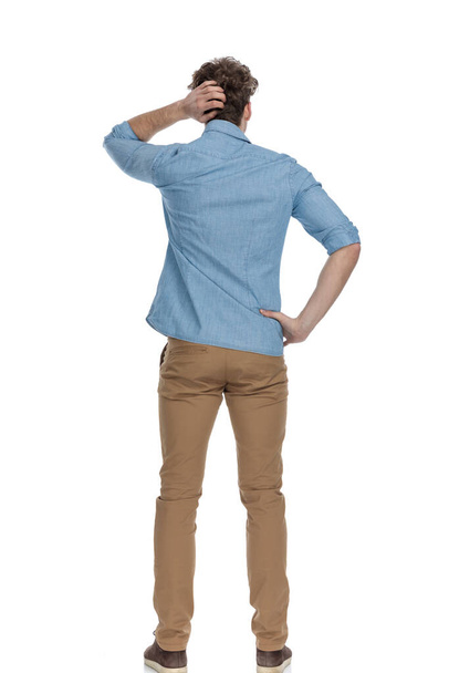 back view of casual man scratching head and thinking of ways to solve difficult problems, standing isolated on white background, full body - Photo, Image