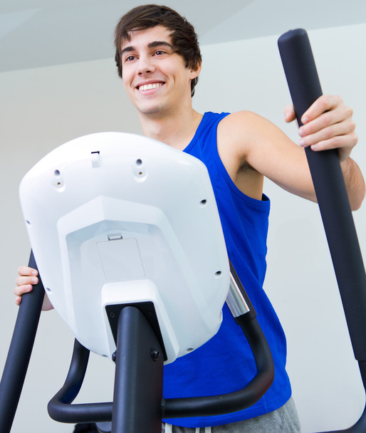Happy young man with elliptic machine in the gym - Φωτογραφία, εικόνα
