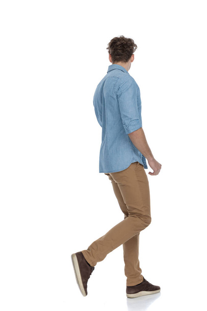 cara casual na camisa jeans olhando para o lado e andando isolado no fundo branco, corpo inteiro
 - Foto, Imagem