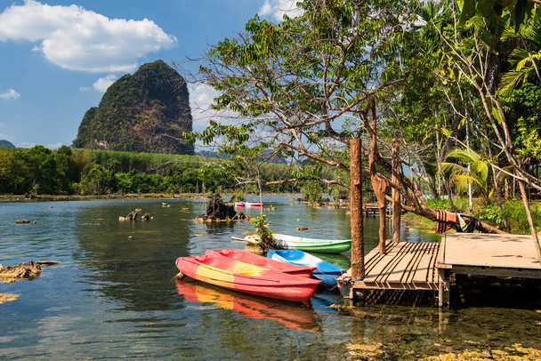 Kayak barcos en pantano con cielo azul y montaña de piedra caliza en Klong Rood, Krabi, Tailandia. Famosa reapertura de destino de viaje después de bloqueo covid-19
. - Foto, imagen
