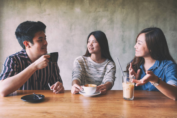 Close-up beeld van drie mensen genoten van praten en het drinken van koffie samen in cafe - Foto, afbeelding