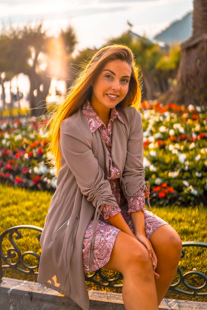 Summer lifestyle. Portrait of young woman near flowerbed - Photo, image