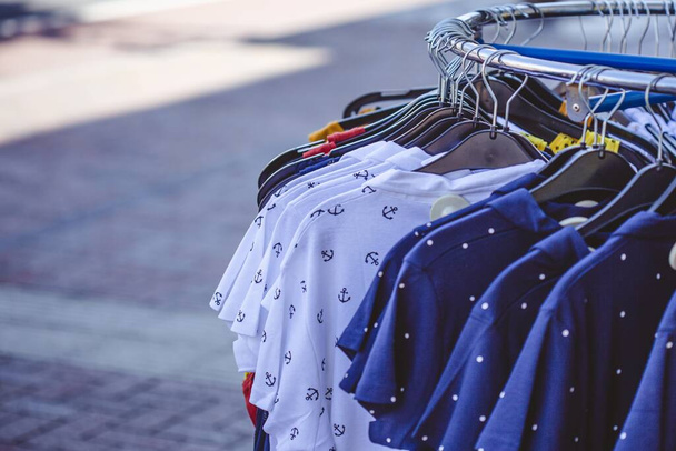 A selective focus shot of some colorful shirts on hangers on the sidewalk - Foto, imagen