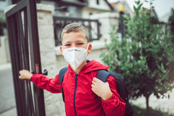 Kind draagt gezichtsmasker tijdens coronavirus en griepuitbraak. De jongen draagt een masker voordat hij naar school gaat om uitbraak van besmettelijke ziekten en stof in de lucht te voorkomen. - Foto, afbeelding