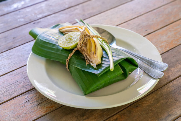 Накрытая банановым листом тайская еда готова к подаче. Внутри банановый лист является PadThai, традиционный Таиланд Жареная лапша с креветками
. - Фото, изображение