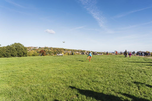 LONDON, UNITED KINGDOM - Oct 27, 2019: A person kicks a ball at Parliament Hill Viewpoint in Hampstead Heath, a large park in London, UK. - 写真・画像