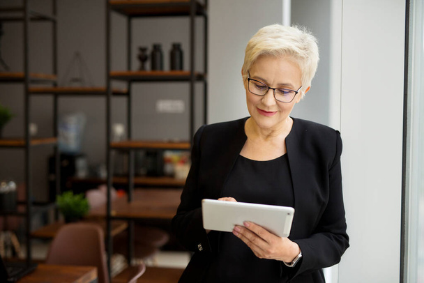 beautiful stylish woman aged with a tablet in her hands at work - Photo, image
