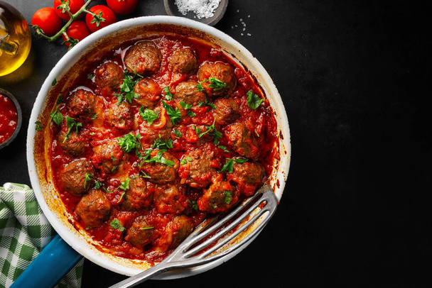 Tasty fried meatballs with tomato and vegetable sauce on pan. View from above with copy space.  - Foto, afbeelding