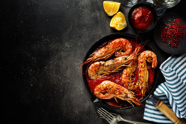 Roasted shrimps with spices and garlic in tomato sauce served on pan on dark background.  - Foto, imagen
