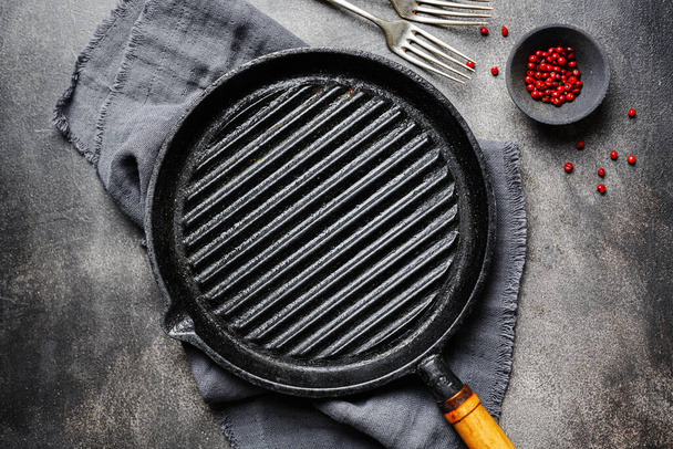 Empty old iron grill pan with napkin on dark background. Cooking concept.  - Fotografie, Obrázek